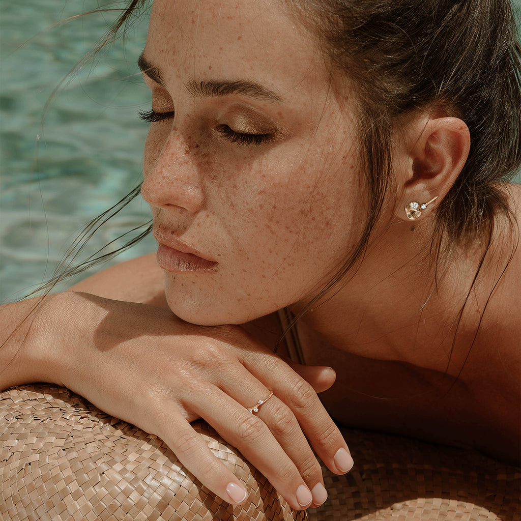 Tage stud and salouen studs worn by a women laying by the pool